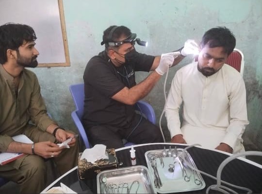 An ENT specialist examining a patient's ear at a free medical camp held by Ahmed Hospital